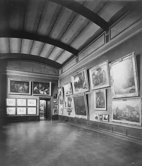 Historische Fotografie von Ausstellungsräumen der Nationalgalerie in Berlin aus dem Jahr 1879. Sie zeigen bis oben behängte Wände mit Gemälden aus der Sammlung des Bankiers Wagener.